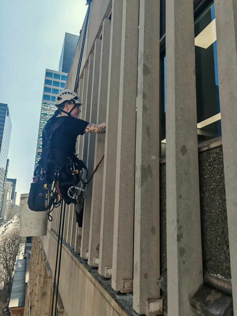 A Tower Window Cleaning rope-access technician working down a stone-columned facade in Melbourne
